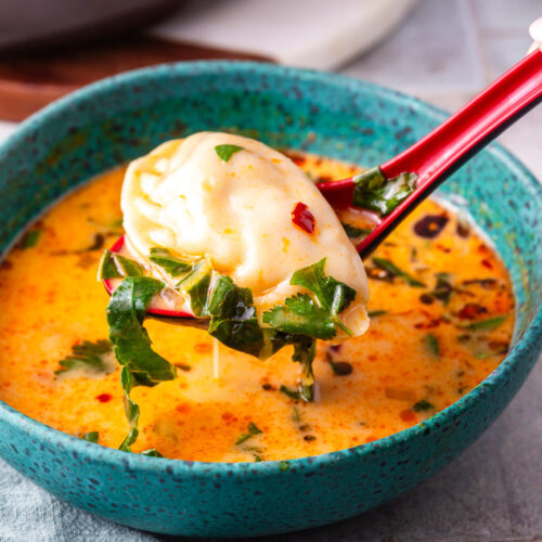 Close up image of a potsticker in curry broth..