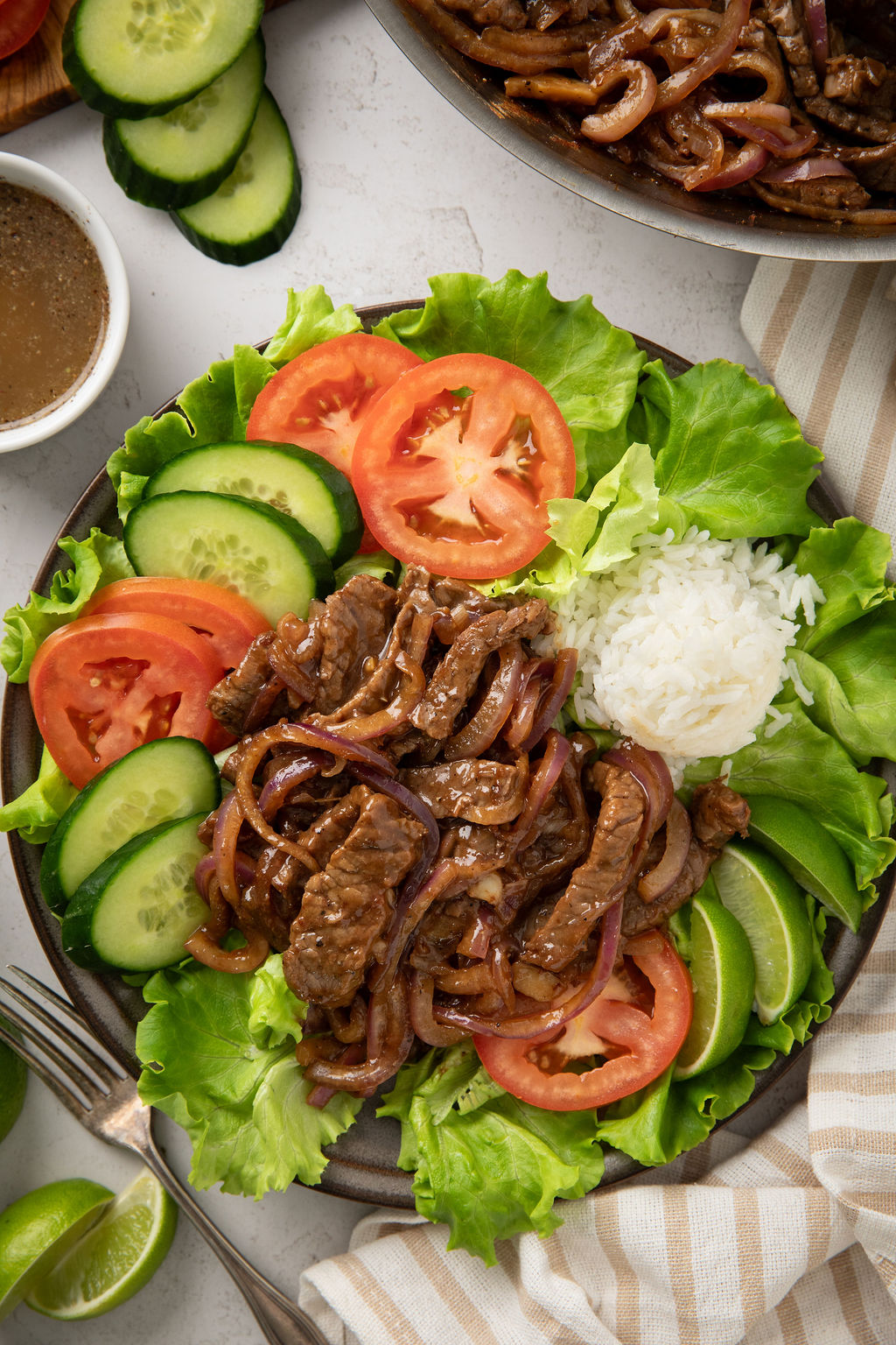 Overhead image of a plate of shaking beef with vegetables and rice.
