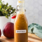 A glass bottle filled with homemade peach sauce for making summer drinks.