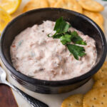 A ceramic bowl of smoked salmon dip surrounded by ritz crackers.